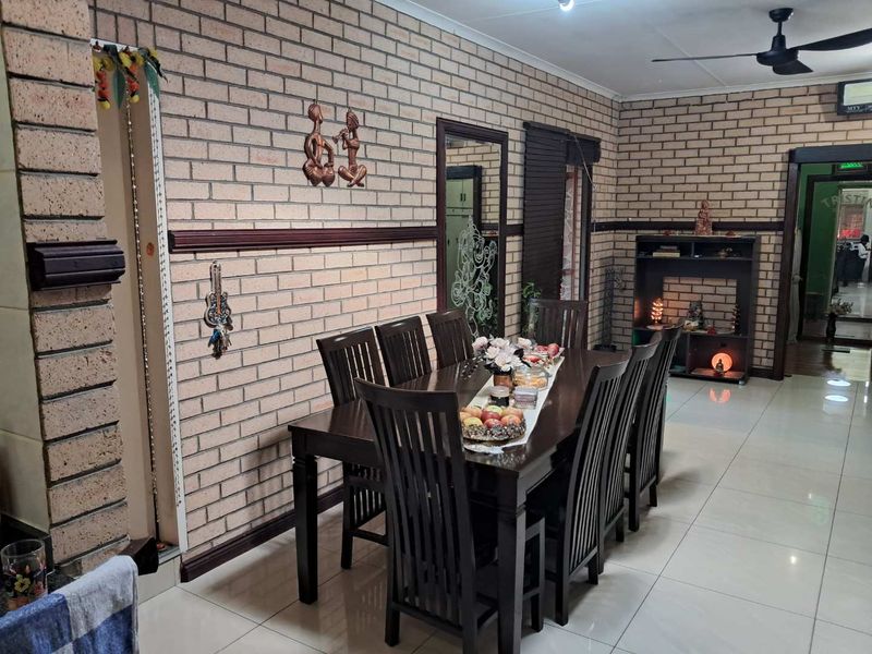 Dining area featuring exposed brick walls, tiled flooring, and a ceiling fan, creating a rustic and functional space for family meals.
