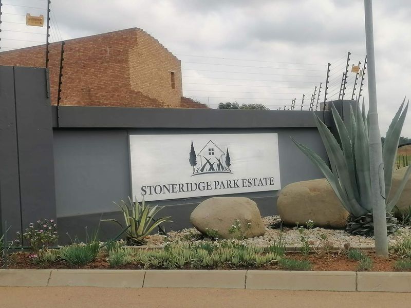 Entrance signage and boundary wall for Stoneridge Park Estate, featuring electric fencing and landscaped garden beds.
