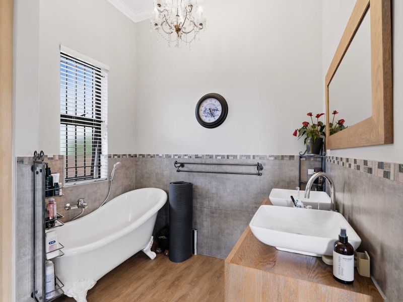 A well-appointed bathroom featuring a classic clawfoot bathtub, double vessel sinks on a wooden vanity, and elegant tiled wall finishes.