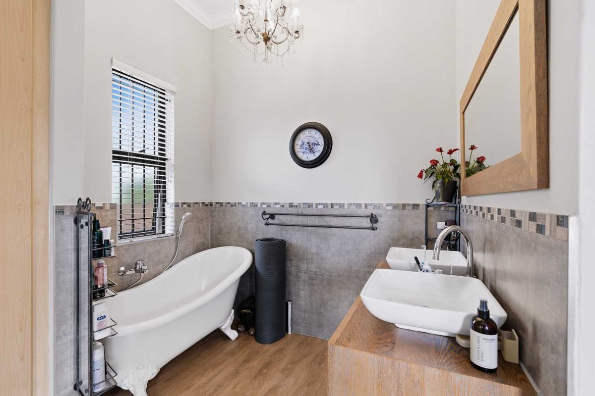 A well-appointed bathroom featuring a classic clawfoot bathtub, double vessel sinks on a wooden vanity, and elegant tiled wall finishes.