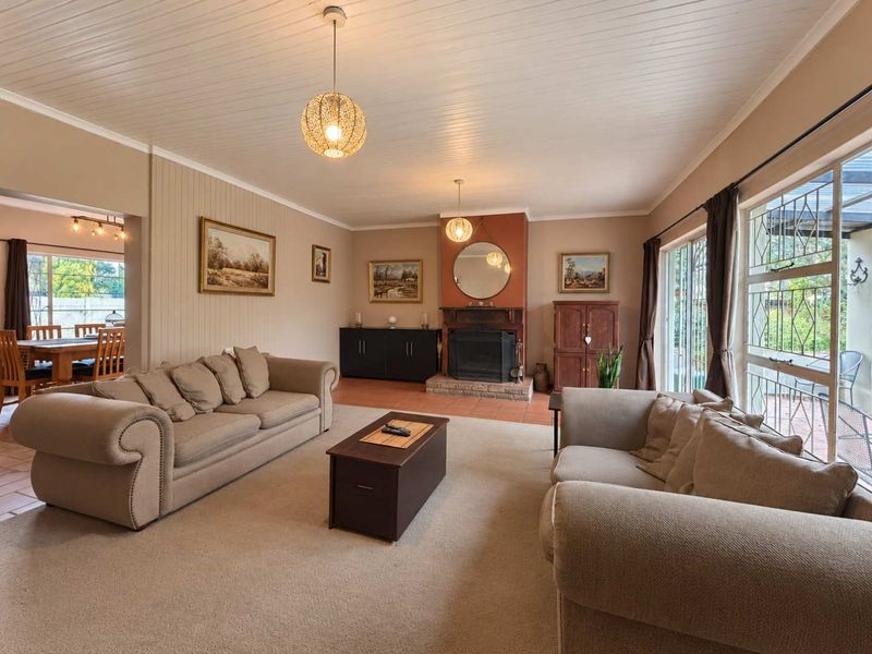 Spacious living room featuring a fireplace with a tiled hearth, timber-clad ceiling, and large sliding glass doors providing access to the patio.