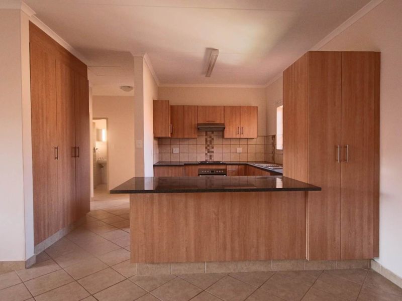 A functional kitchen featuring wood-finish cabinetry, granite countertops, a breakfast nook, and built-in appliances, with tiled flooring throughout.