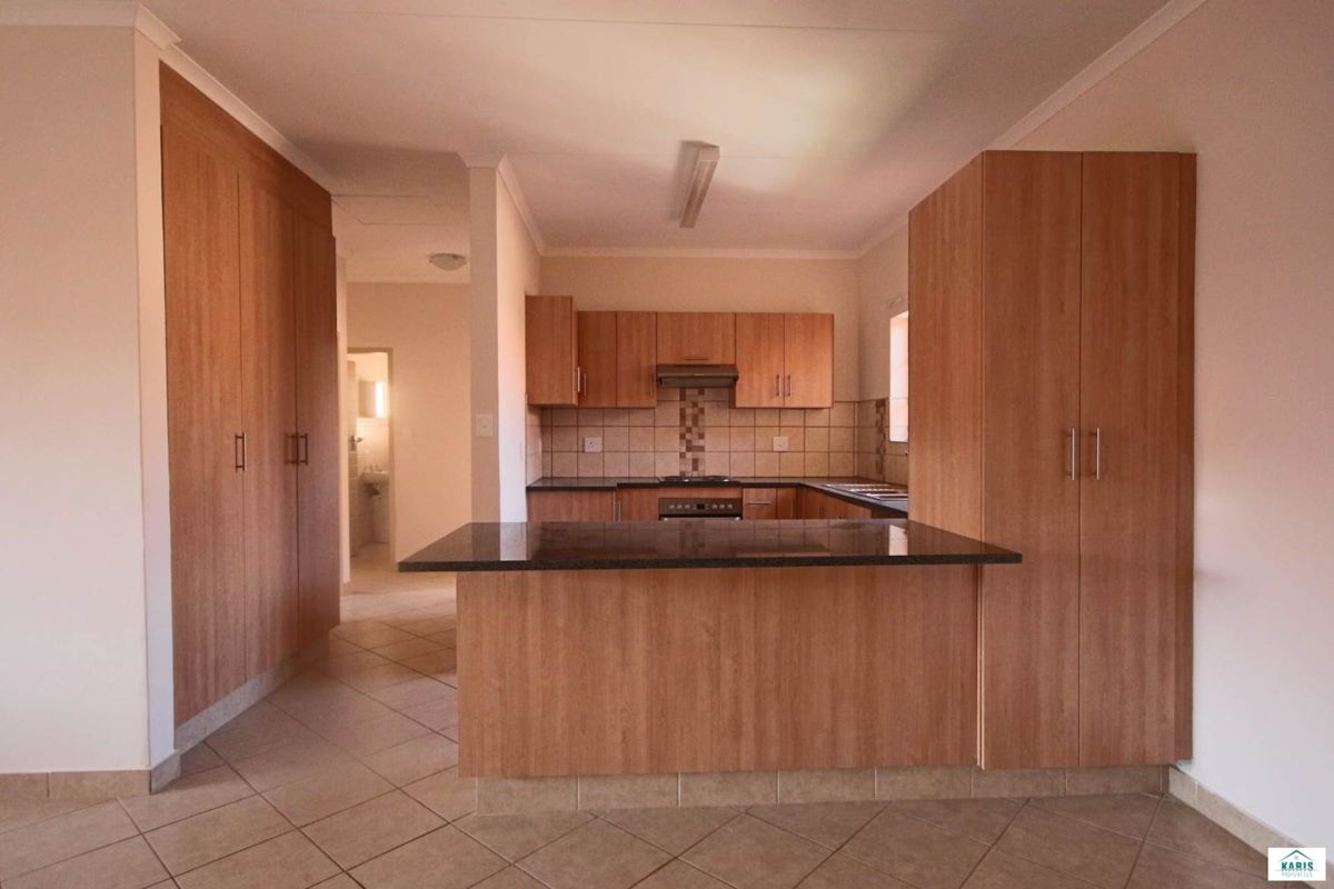 A functional kitchen featuring wood-finish cabinetry, granite countertops, a breakfast nook, and built-in appliances, with tiled flooring throughout.