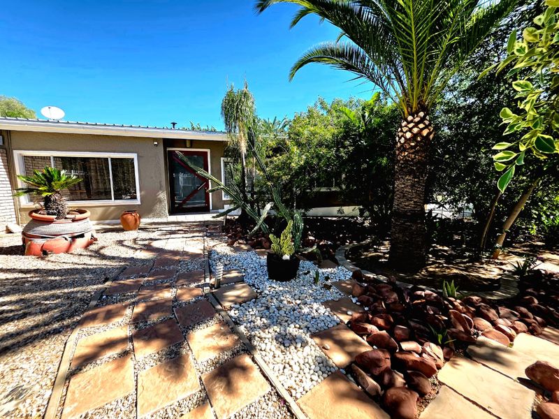 Front exterior view of the house featuring a landscaped garden with a paved walkway leading to the main entrance.