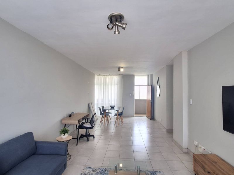Spacious open-plan living and dining area featuring neutral tiled flooring, modern ceiling lighting, and direct access to an outdoor balcony space.