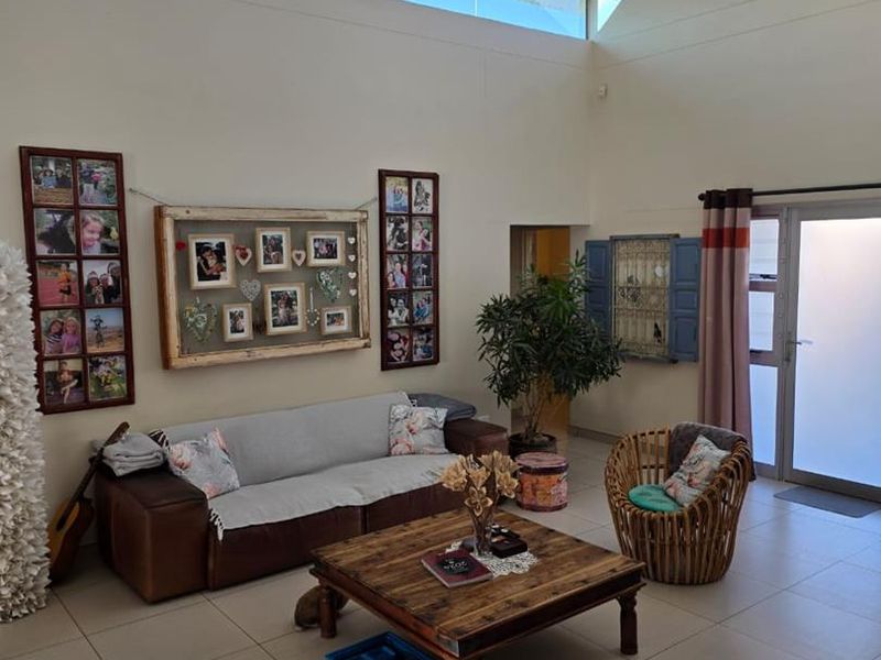 Spacious living room featuring high vaulted ceilings, clerestory windows for natural light, and neutral tiled flooring.