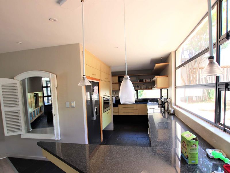 Modern kitchen featuring granite countertops, built-in cabinetry, integrated oven, and large windows providing ample natural light and a view of the garden.