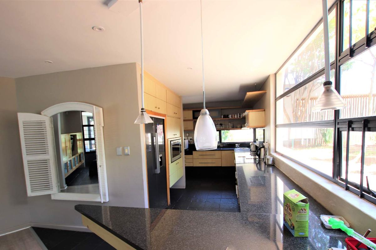 Modern kitchen featuring granite countertops, built-in cabinetry, integrated oven, and large windows providing ample natural light and a view of the garden.