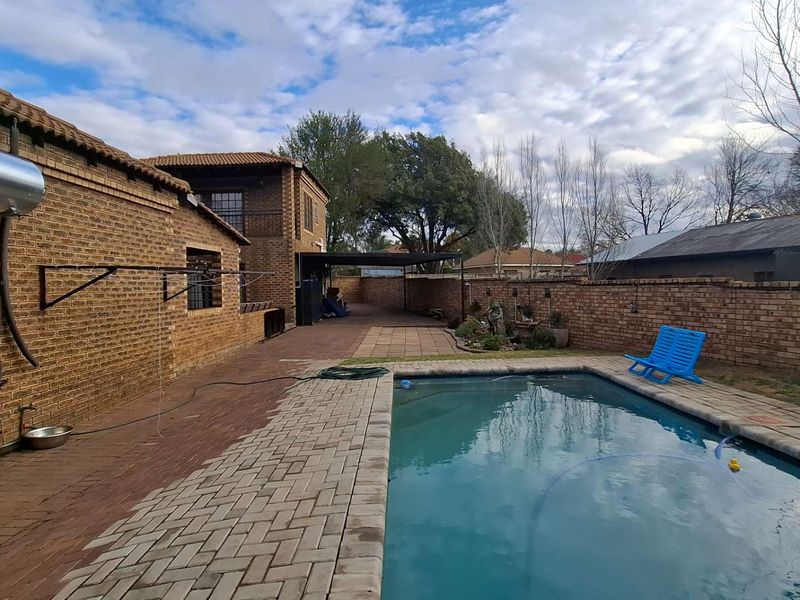 Outdoor pool area featuring brick paving, a boundary wall, and a solar water heater system attached to the main house structure.
