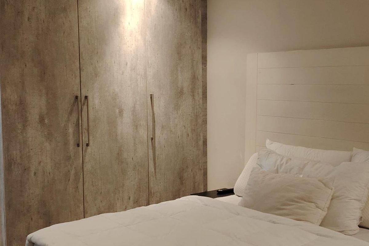 A well-maintained bedroom featuring modern built-in cupboards with a textured finish and integrated recessed lighting.