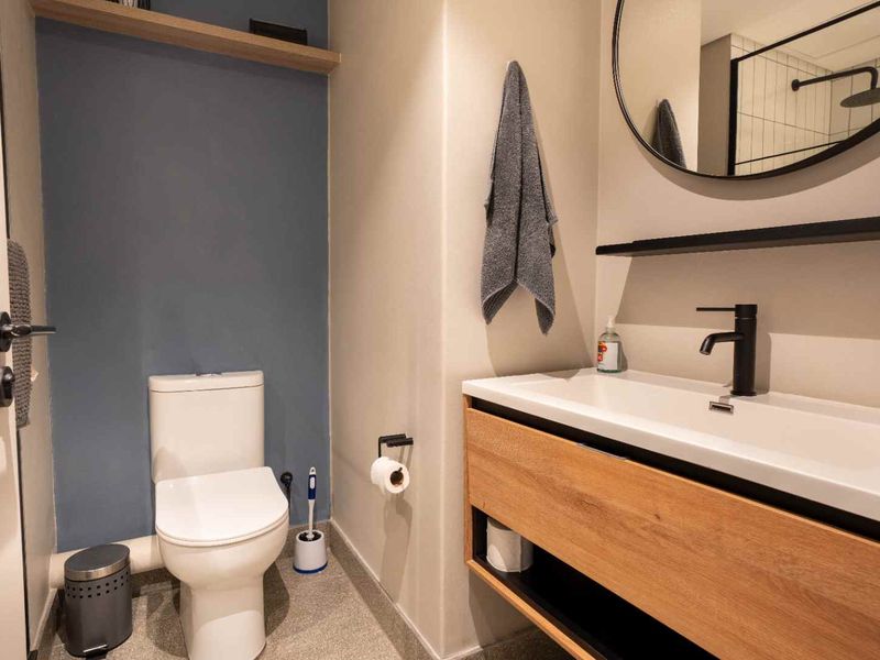 Modern bathroom featuring a wood-finish vanity with integrated sink, matte black fixtures, and a clean, contemporary design aesthetic.