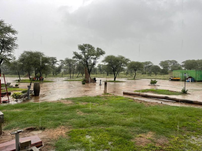 An outdoor garden area on a farm property experiencing heavy rainfall and significant water accumulation on the grounds.