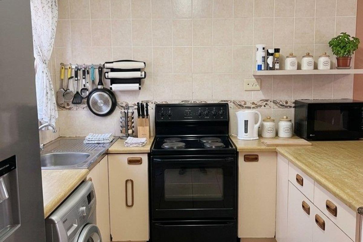 A functional kitchen featuring laminate countertops, ceramic tile backsplash, tiled flooring, and a freestanding electric stove with integrated cabinetry.