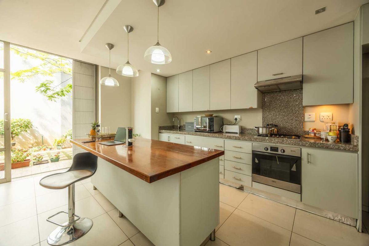 Modern kitchen featuring a central island with a wooden countertop, granite surfaces, built-in oven, gas hob, and direct access to an outdoor patio area.