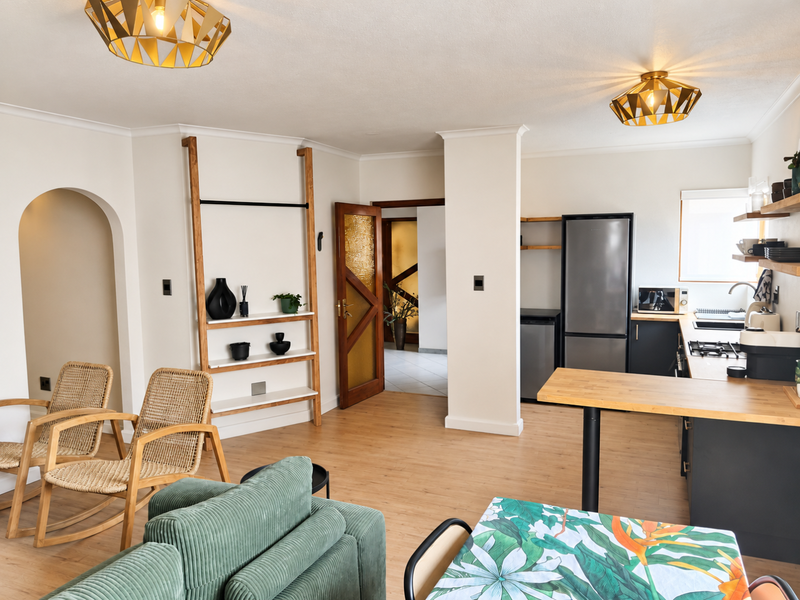 Open-plan living area featuring a modern kitchen with breakfast bar, laminate flooring, and an elegant archway leading to adjacent spaces.