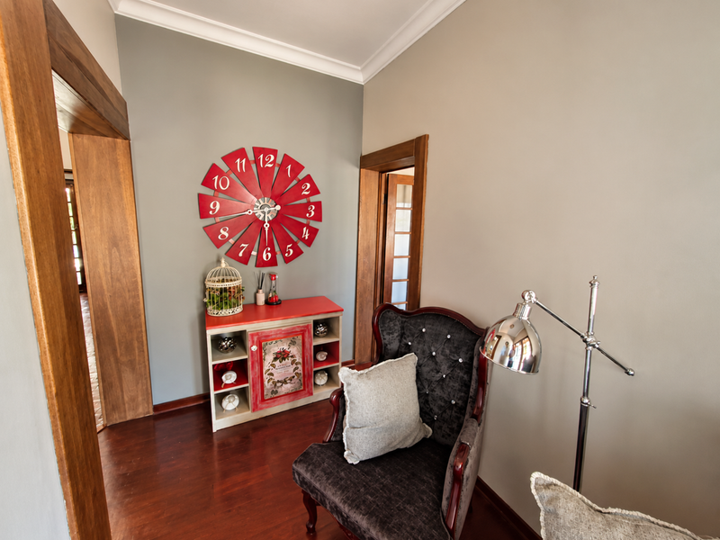 A well-maintained hallway featuring rich hardwood flooring, classic timber door frames, and decorative coved cornicing, creating a warm and inviting transition space.