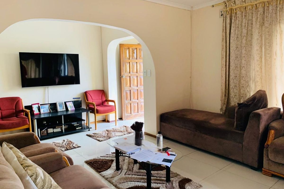 A living room featuring tiled flooring and a distinctive arched doorway leading to an adjacent space with a timber panel door.