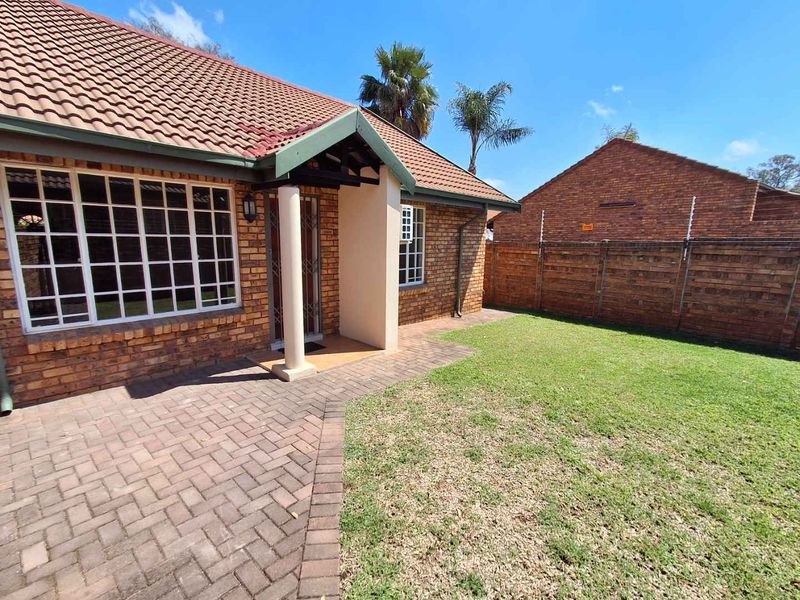 A private rear garden featuring a paved patio area, brick facade, and secure boundary wall with electric fencing.