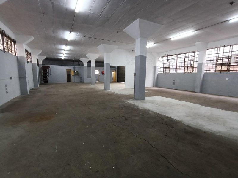 Spacious industrial utility area featuring concrete flooring, structural columns, and security-barred windows, suitable for warehouse or workshop use.