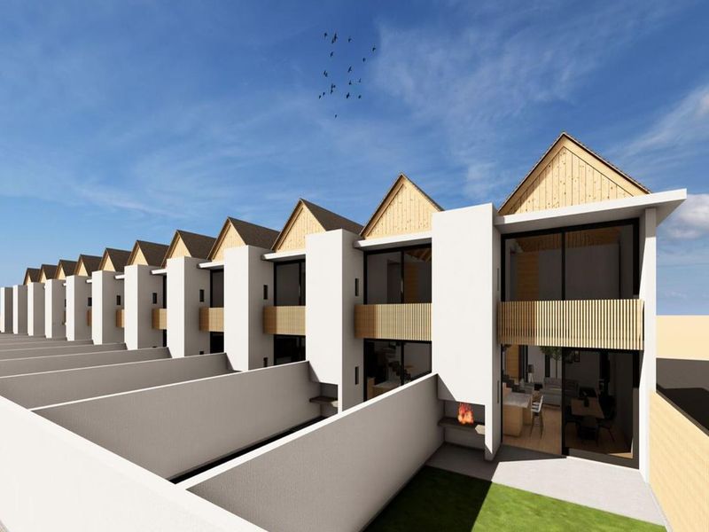A row of modern townhouses featuring rear patios with built-in braais, timber accents, and large sliding doors opening to private garden spaces.