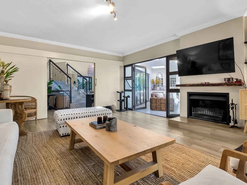 Spacious living room featuring a fireplace with a timber mantelpiece, tiled flooring, and direct access to an outdoor area through glass french doors.