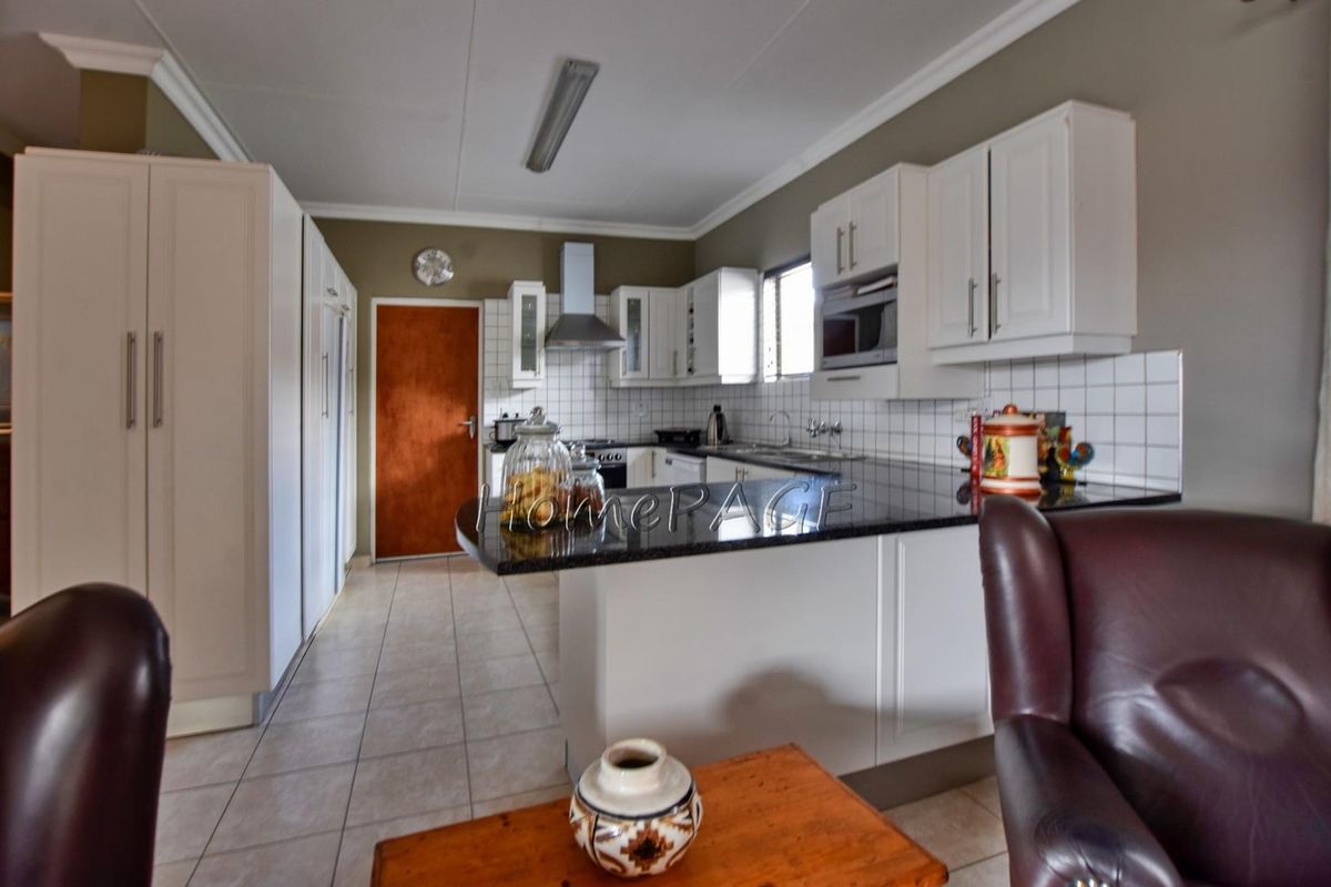 A functional kitchen featuring white cabinetry, dark granite countertops, tiled backsplash, and built-in appliances, including an extractor fan and microwave.