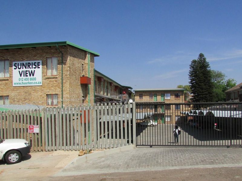 Exterior view of the Sunrise View apartment complex featuring face brick buildings, secure gated access, and covered parking bays.