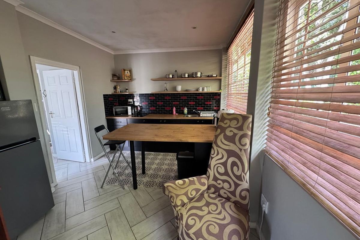 Compact kitchen featuring dark cabinetry, subway tile backsplash, floating shelving, and tiled flooring with a breakfast bar area.