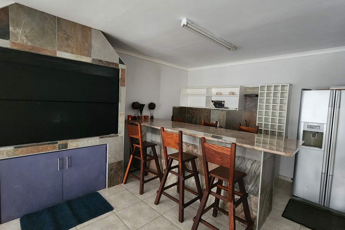 Entertainment area featuring a built-in braai with stone cladding, a stone-topped breakfast bar, and built-in shelving units.