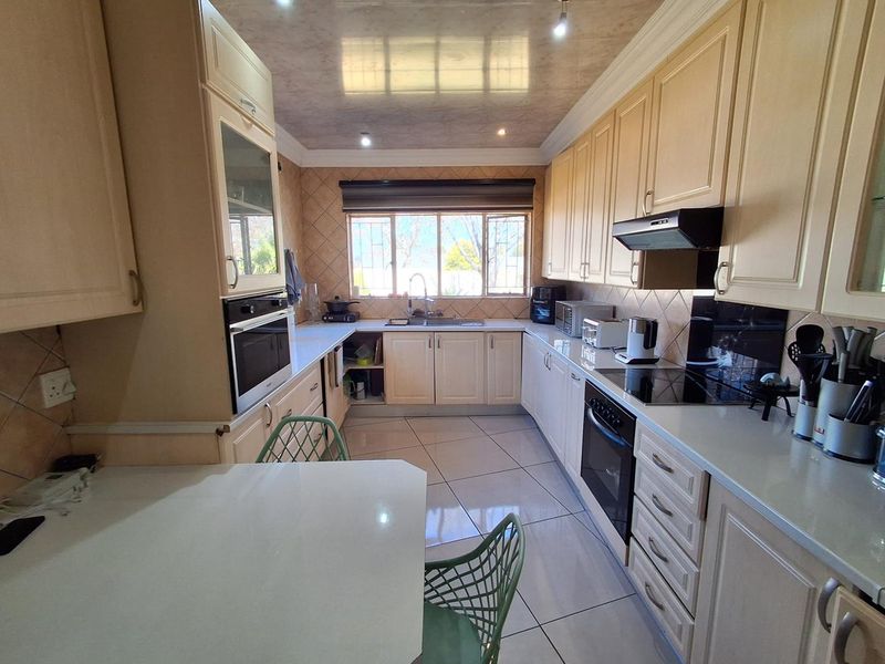 A functional kitchen featuring built-in cabinetry, integrated oven and hob, tiled flooring, and a tiled backsplash with ample counter space.