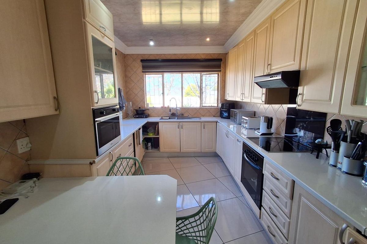 A functional kitchen featuring built-in cabinetry, integrated oven and hob, tiled flooring, and a tiled backsplash with ample counter space.
