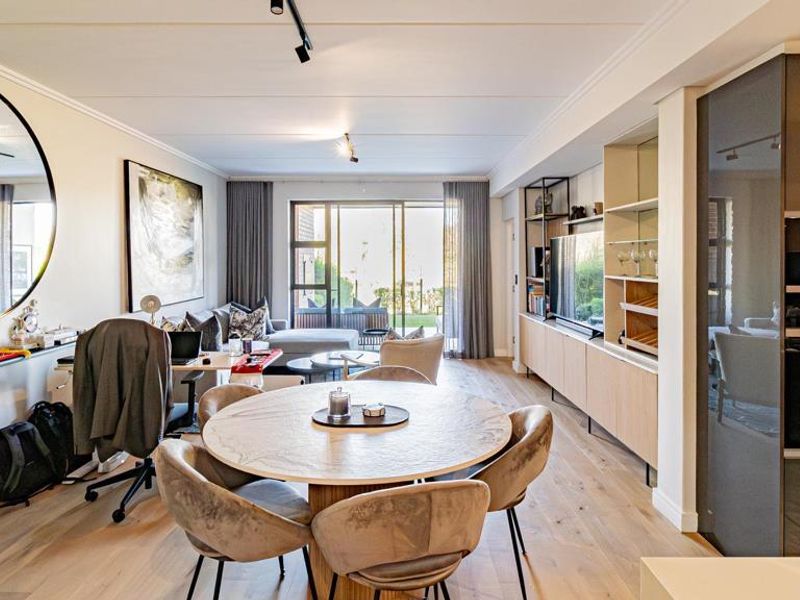 Modern open-plan living area featuring high-end integrated kitchen appliances, custom built-in cabinetry, track lighting, and seamless access to the outdoor patio.