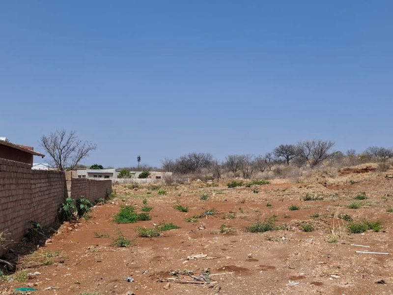 A vacant residential plot featuring perimeter brick walls and electric fencing, offering a clear space for future development.