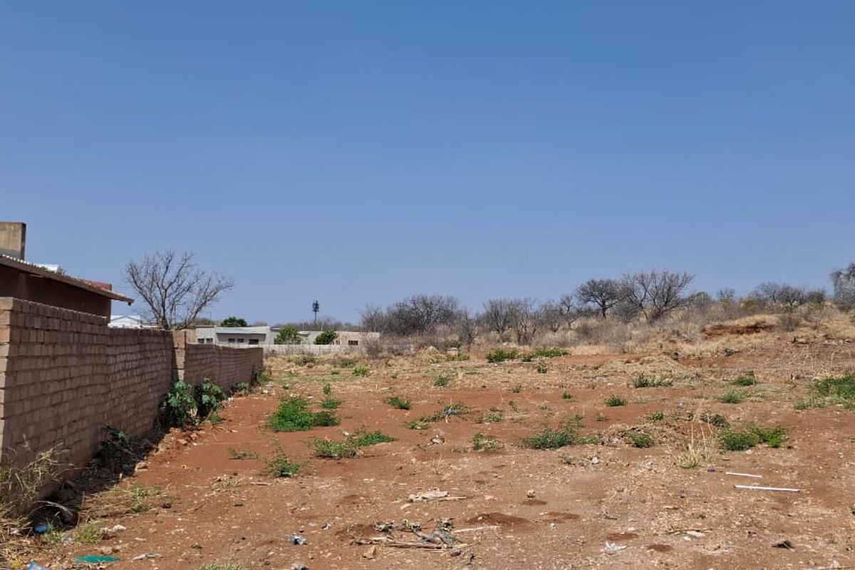 A vacant residential plot featuring perimeter brick walls and electric fencing, offering a clear space for future development.