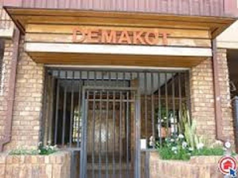 Front entrance of the property featuring a brick facade, timber detailing, and a secure metal gate.