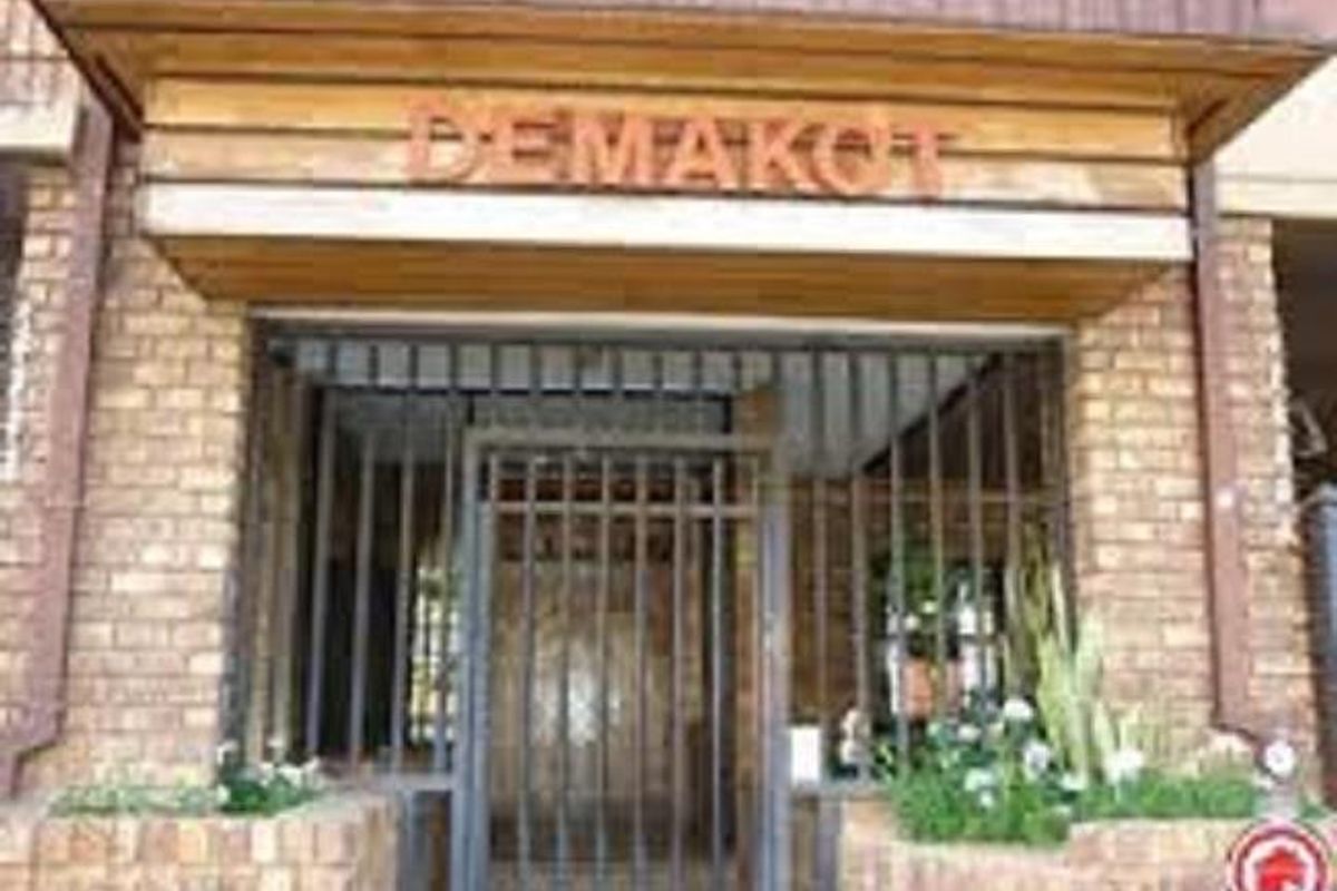 Front entrance of the property featuring a brick facade, timber detailing, and a secure metal gate.