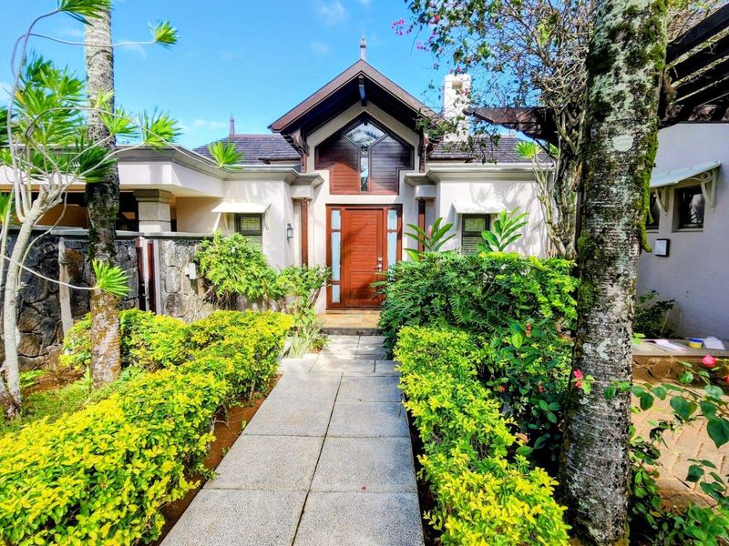 A well-maintained front entrance featuring a paved walkway, lush landscaped garden, and a distinctive timber-framed facade with a pitched roof design.