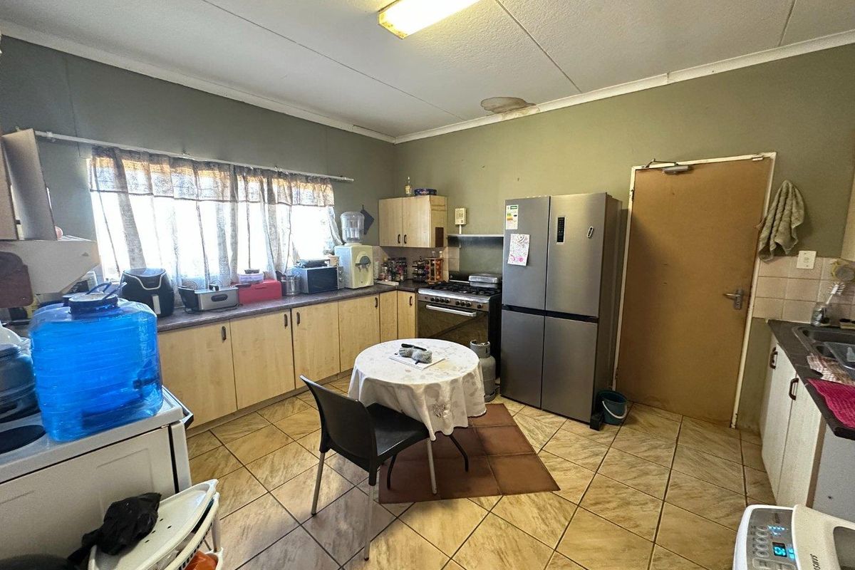 A functional kitchen featuring laminate cabinetry, tiled flooring, and a built-in stove, requiring cosmetic updates to modernize the space.