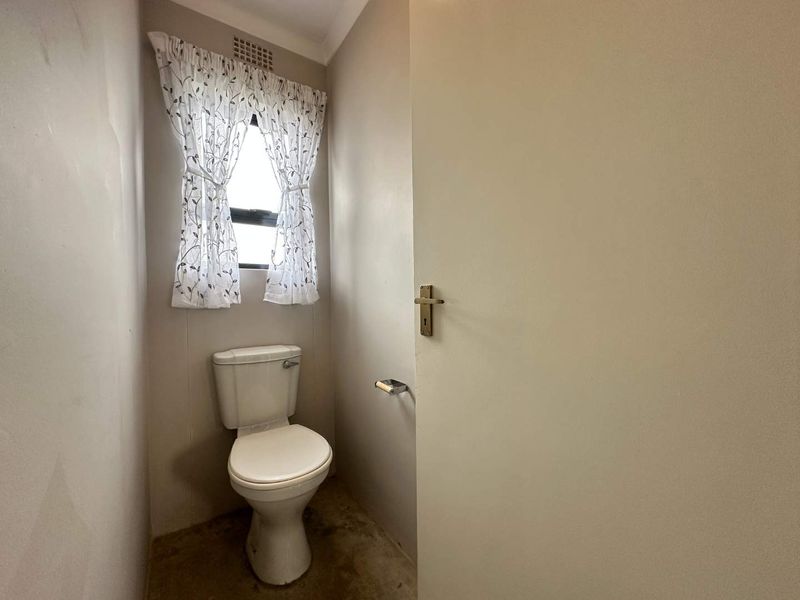 A small, functional bathroom featuring a standard toilet and basic finishes, currently in need of cosmetic updates.