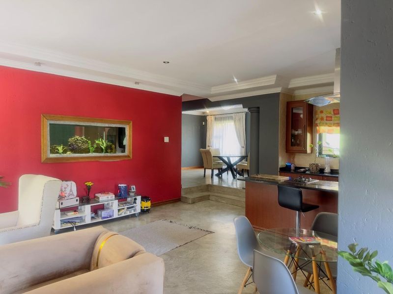Open plan living area featuring a kitchen with breakfast bar, dining space on a raised platform, and a built-in wall aquarium.