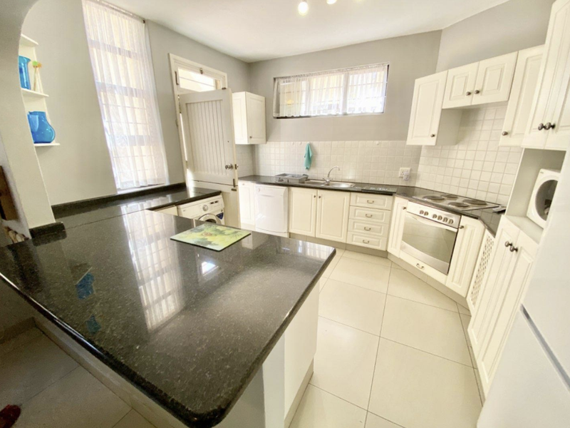 A functional kitchen featuring granite countertops, built-in cabinetry, a tiled backsplash, and integrated oven and hob, offering a clean and practical workspace.