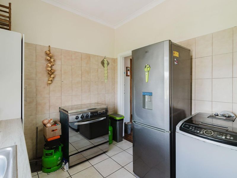 A functional kitchen area featuring tiled splashbacks, tiled flooring, and space for essential appliances, offering a practical layout for daily cooking and utility needs.