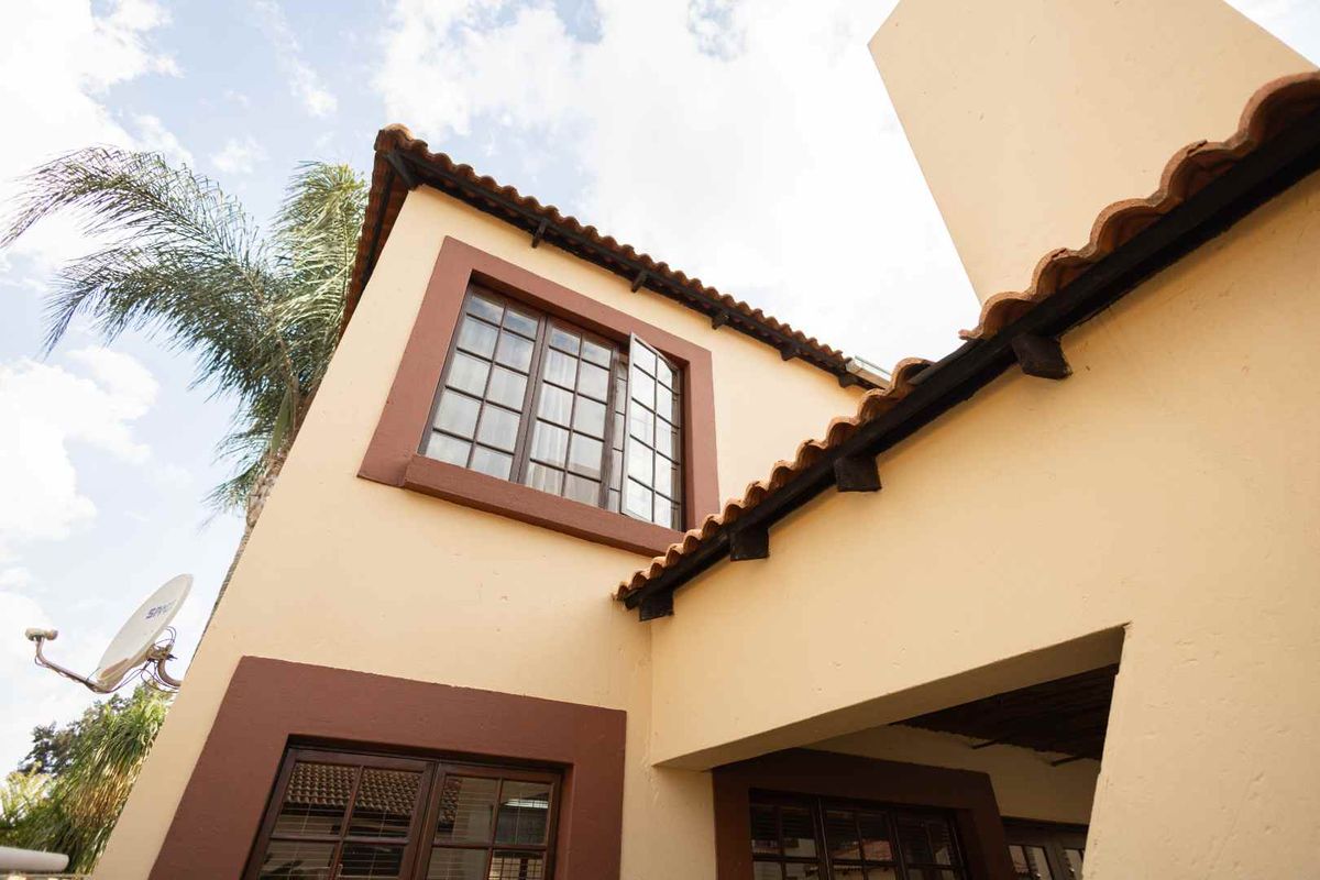 Exterior view of the townhouse facade featuring traditional terracotta roof tiles, brown window frames, and a chimney stack.