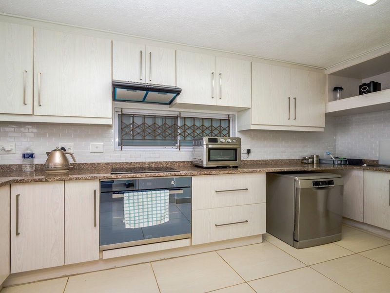 A functional kitchen featuring light wood-grain cabinetry, granite countertops, subway tile backsplash, and integrated appliances including an oven and hob.