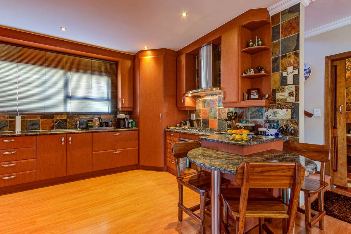 A well-maintained kitchen featuring warm wooden cabinetry, granite countertops, a slate tile backsplash, and integrated appliances with a breakfast nook area.