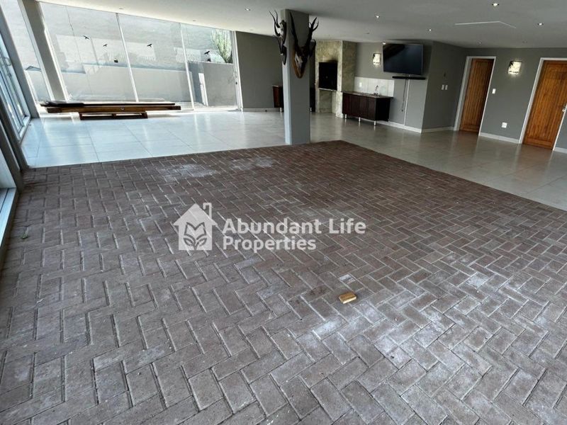 Spacious open-plan living area featuring a built-in bar, brick and tile flooring, and large sliding glass doors leading to the exterior.