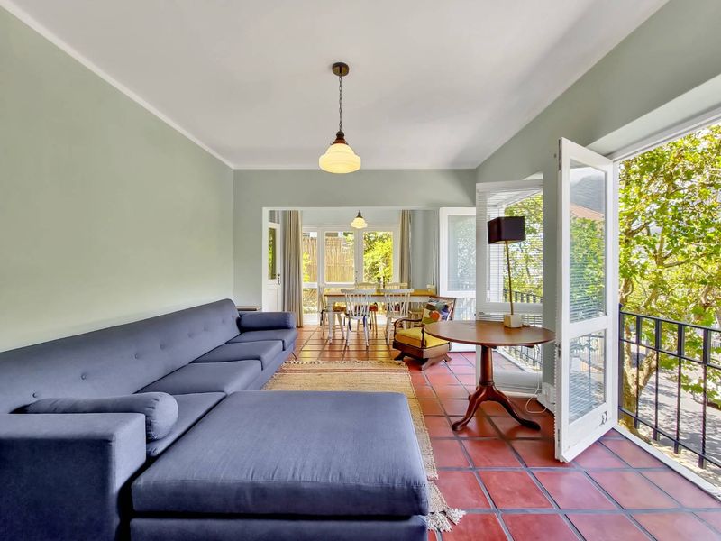 Bright open-plan living and dining area featuring terracotta floor tiles and direct access to a balcony through double glass doors.