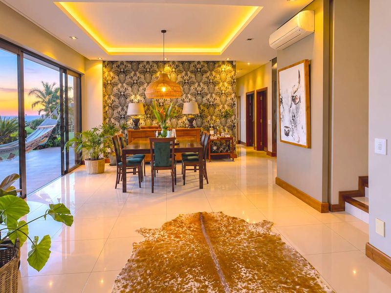 Elegant dining area featuring recessed cove lighting, large sliding glass doors opening to a patio, and polished tile flooring.