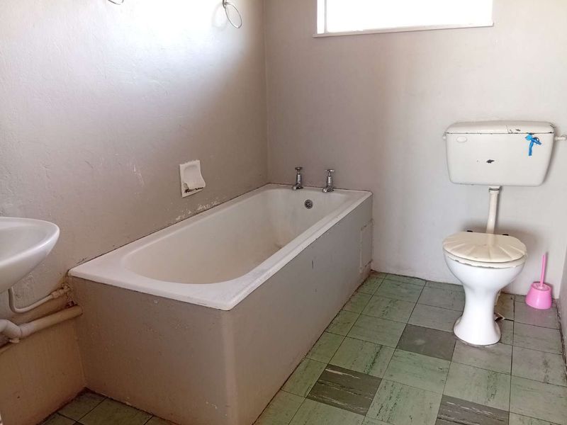 A functional bathroom featuring a built-in bathtub and standard toilet, offering a blank canvas for modernization and renovation.