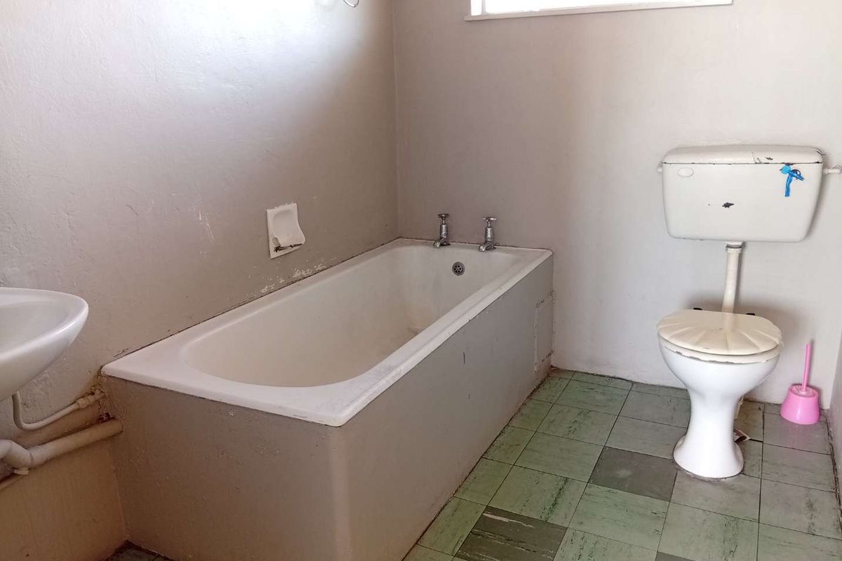 A functional bathroom featuring a built-in bathtub and standard toilet, offering a blank canvas for modernization and renovation.